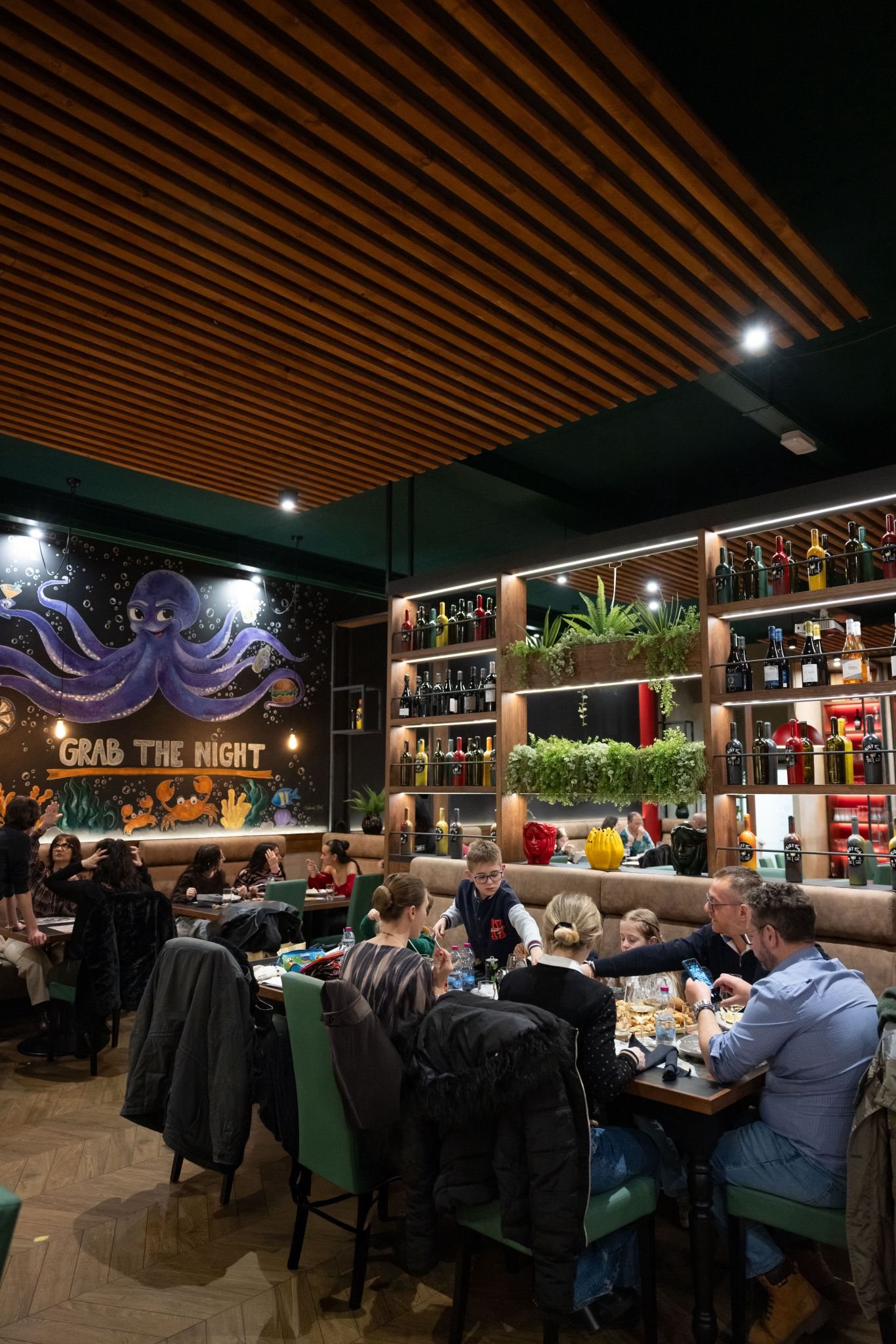 La sala di Enjoy Fish con il murale Grab the Night e la parete di bottiglie